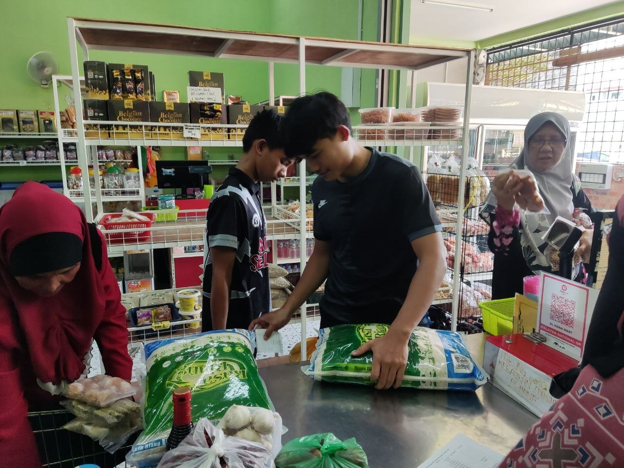 Penerima menebus barangan bantuan bulanan di kaunter