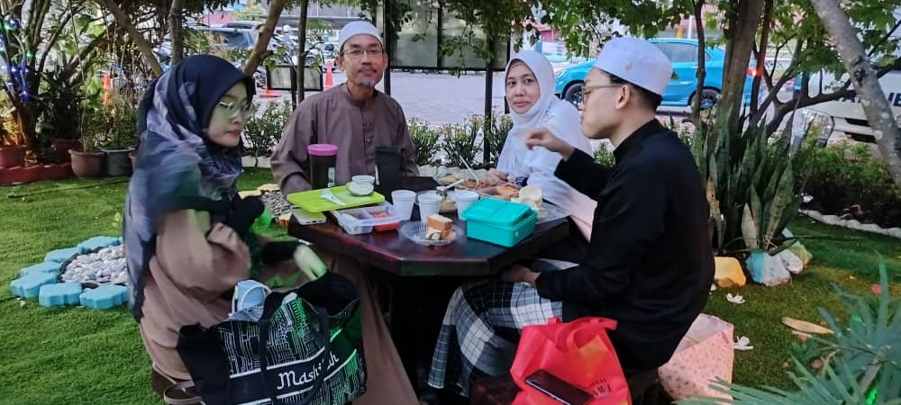 Keluarga berbuka puasa di ruang taman kafe masjid