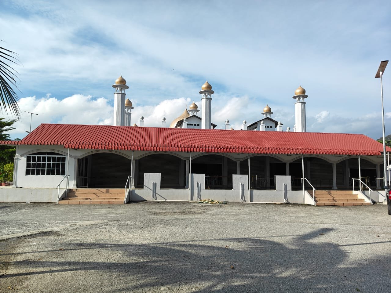 Dewan Ar-Rahman dilihat dari luar, dengan menara dan kubah Masjid Al-Hana' Kuah di latar belakang